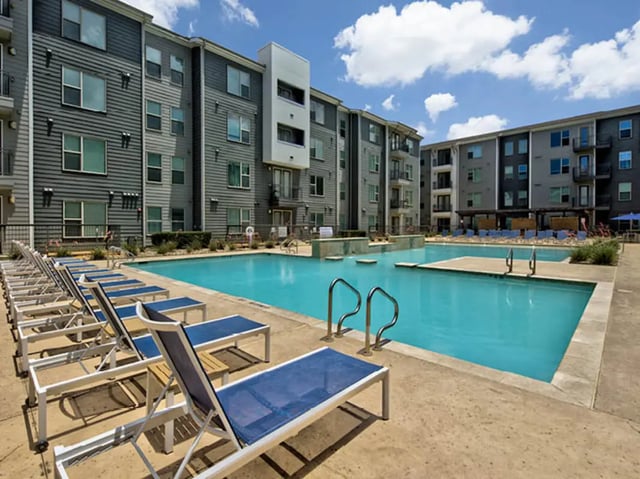 Apartment complex with swimming pool and lounge chairs exterior at The Arlie in Arlington Student Accommodation