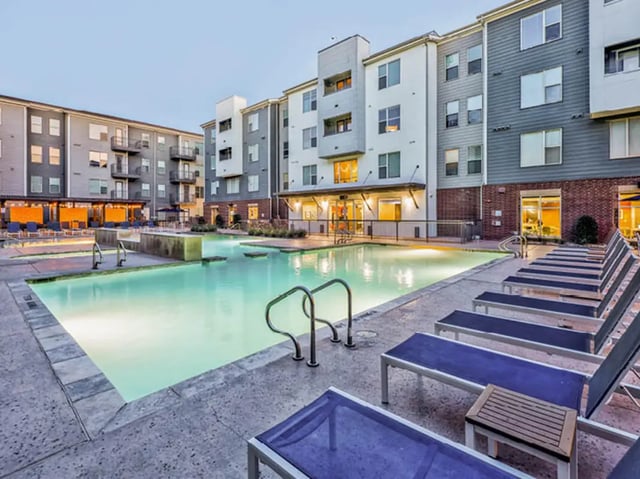 Apartment buildings with pool and lounge chairs exterior at The Arlie in Arlington Student Accommodation