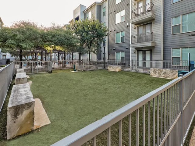 Fenced green dog park with seating area exterior at The Arlie in Arlington Student Accommodation