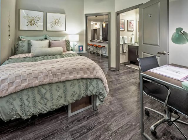 Bed with desk and kitchen visible Bedroom at The Arlie in Arlington Student Accommodation