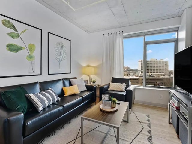 Black leather sofa with pillows coffee table living room at The Summit at University City in Philadelphia Student Accommodation