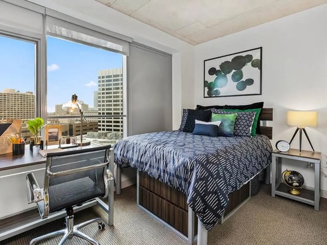 Bed desk chair and cityscape view bedroom at The Summit at University City in Philadelphia Student Accommodation