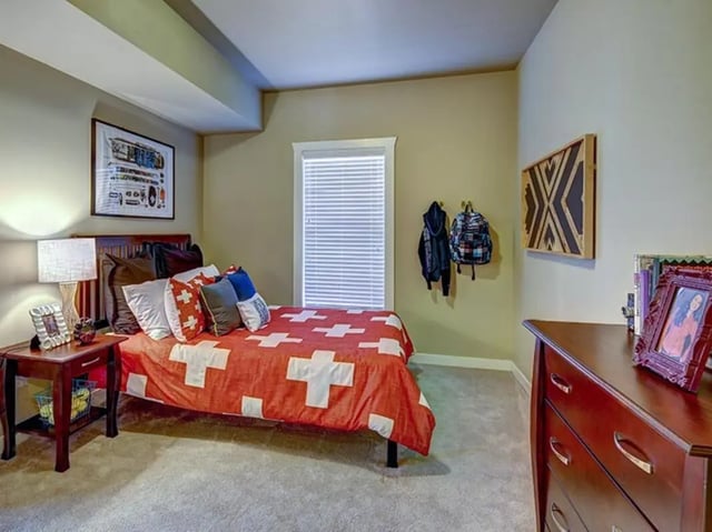 Bed with red blanket pillows dresser framed art bedroom at The Cottages of Durham in Durham Student Accommodation