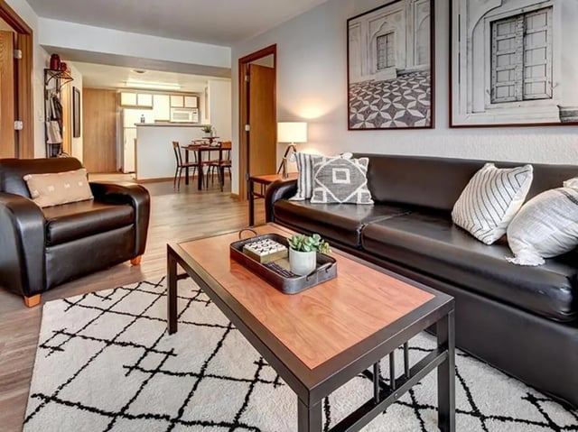 Black leather sofa and armchair patterned rug living room at The Tower at Third in Champaign Student Accommodation