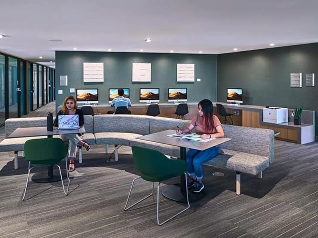 Students using computers and printers in communal study area at Plaza Verde in Irvine Student Accommodation
