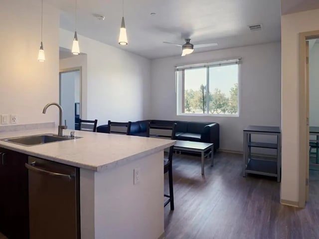 Modern kitchen island black couch window living room at Plaza Verde in Irvine Student Accommodation