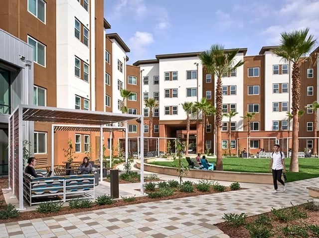 Outdoor lounge area with students and buildings exterior at Plaza Verde in Irvine Student Accommodation