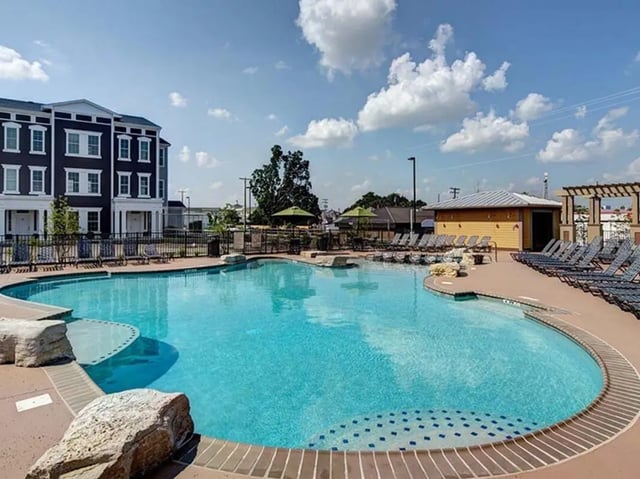 Apartment building with pool and lounge chairs exterior at The Townhomes at Newtown Crossing in Lexington Student Accommodation