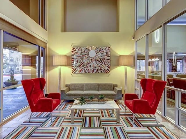 Red chairs couch artwork lamps patterned rug living room at Hilltop Townhomes in Flagstaff Student Accommodation