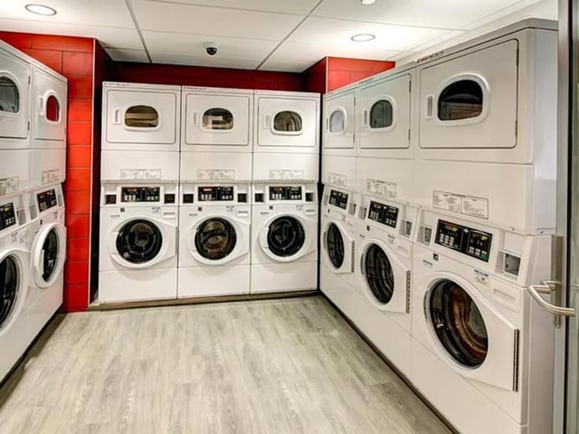 Stacked washing machines and dryers on grey floor Laundry area at Honors Academic Village in Toledo Student Accommodation