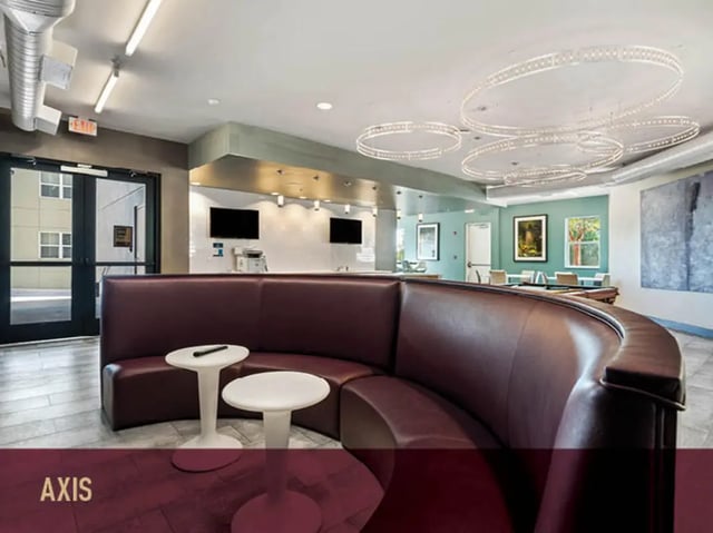 Maroon curved sofa with white tables common area at Stadium Centre - The Axis in Tallahassee Student Accommodation