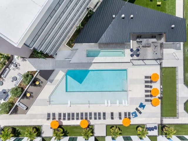 Pool lounge chairs umbrellas and building exterior aerial view at Apella on Newport in Tampa Student Accommodation
