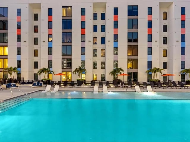 Modern building lounge chairs pool and palm trees exterior at Apella on Newport in Tampa Student Accommodation