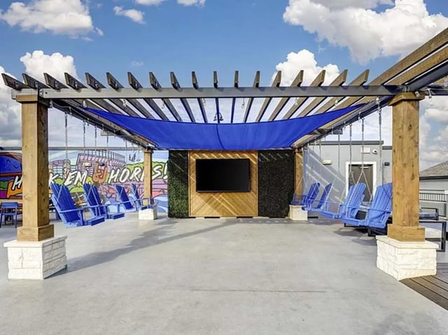 Outdoor lounge area with swings and TV exterior at The Block on 28th in Austin Student Accommodation