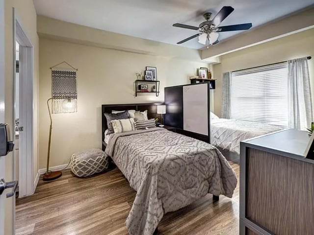 Two beds wall hanging floor lamp bedroom at The Block on 28th in Austin Student Accommodation
