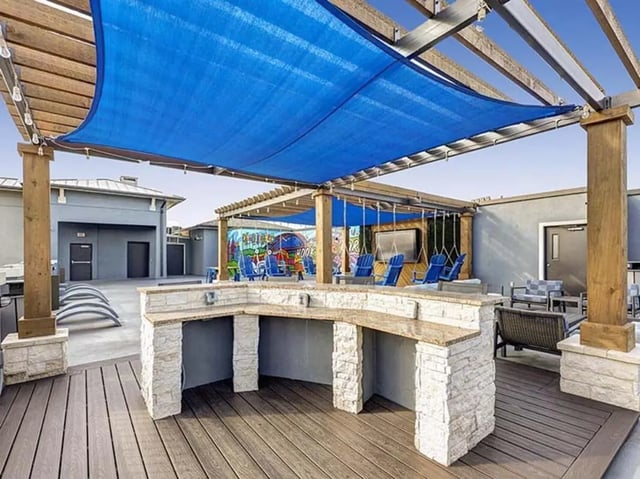 Outdoor bar with lounge chairs and swings patio area at The Block on 28th in Austin Student Accommodation