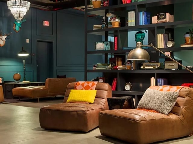 Leather lounge chairs on floor with bookshelves living room at The James in Madison Student Accommodation