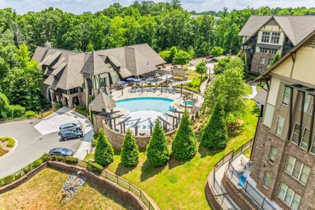 Apartment buildings surrounding pool and lush trees exterior at Arcadia Student Living in Charlotte Student Accommodation