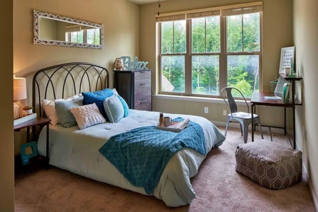 Bed with blue blankets pillows mirror desk and chair bedroom at Arcadia Student Living in Charlotte Student Accommodation