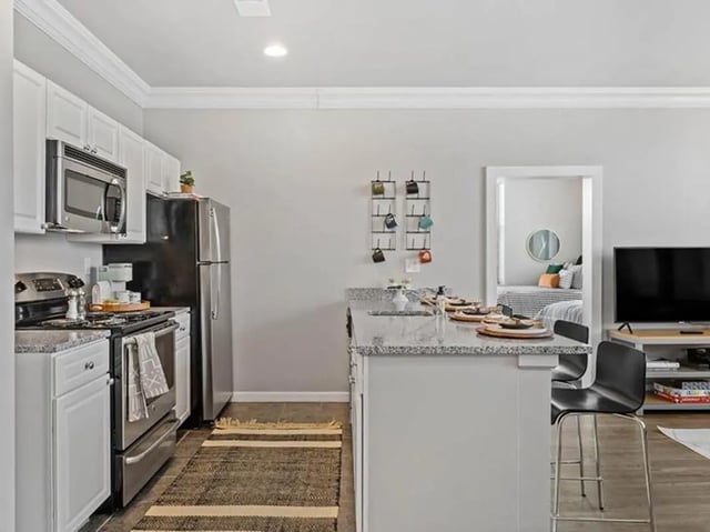 Kitchen with fridge stove island and bedroom visible living room at University Crossings in Philadelphia Student Accommodation