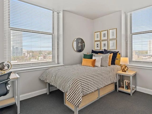 Bed with polka dot comforter framed art clock desk Bedroom at University Crossings in Philadelphia Student Accommodation