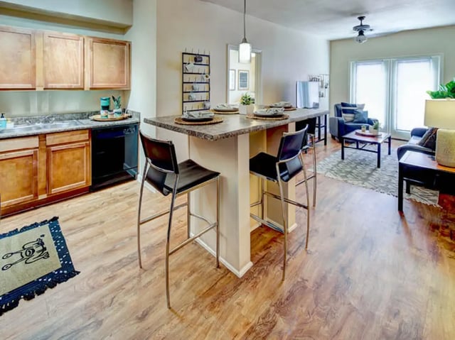 Kitchen island with stools and living area Living room at Union in Waco Student Accommodation
