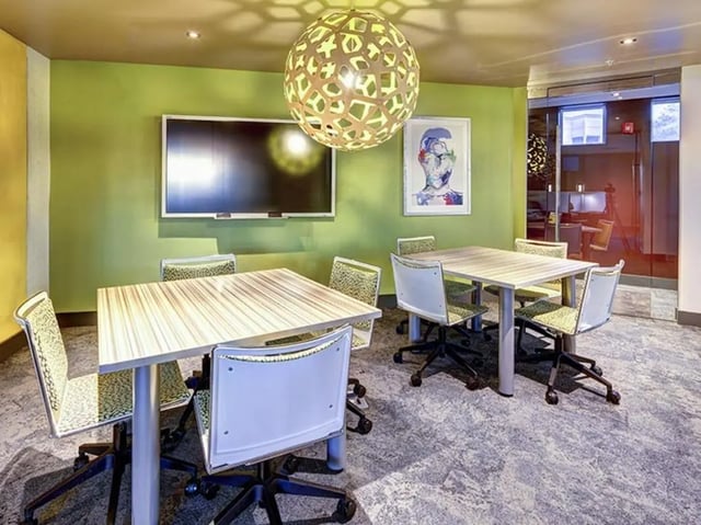 Two tables chairs and wall mounted TV study area at University Crossings Charlotte in Charlotte Student Accommodation
