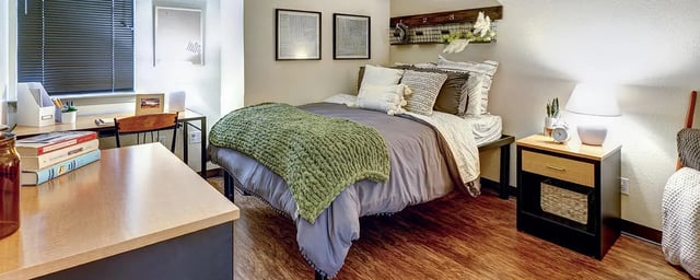 Bed with green throw desk and books Bedroom at The Callaway House in College Station Student Accommodation