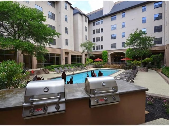 Two stainless steel grills poolside lounge chairs exterior at The Callaway House in College Station Student Accommodation