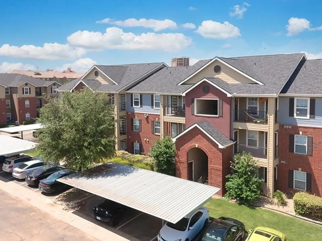 Apartment buildings with parking garage exterior at University Trails in Lubbock Student Accommodation