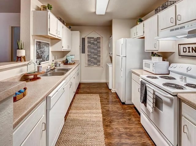 White cabinets refrigerator stove sink kitchen area at University Trails in Lubbock Student Accommodation