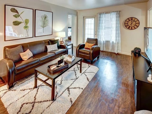 Leather couch armchair coffee table rug living room at University Trails in Lubbock Student Accommodation