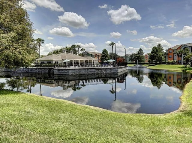 Apartment buildings surrounding a serene lake exterior at The Village At Science Drive in Orlando Student Accommodation
