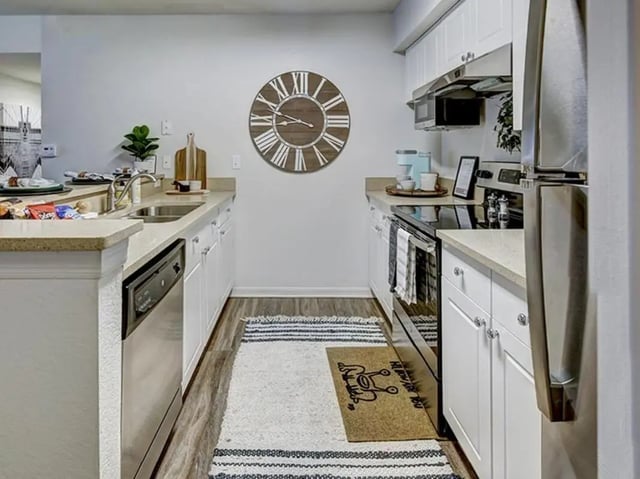 Clock on wall sink dishwasher oven kitchen at The Village At Science Drive in Orlando Student Accommodation
