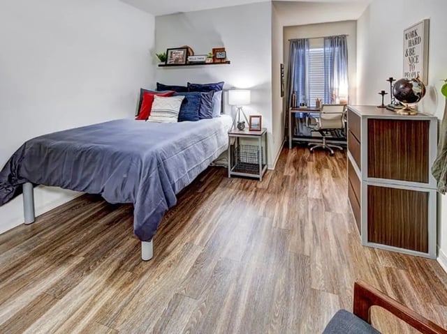 Bed with blue bedding desk with chair bedroom at The Village At Science Drive in Orlando Student Accommodation