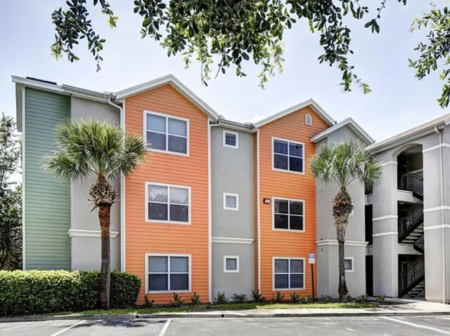 Colorful student housing building with palm trees exterior at The Village At Science Drive in Orlando Student Accommodation