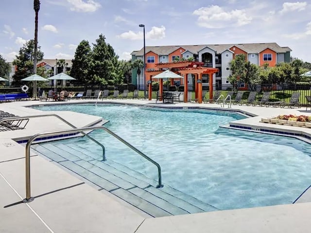 Swimming pool with loungers pergola and apartment buildings exterior at The Village At Science Drive in Orlando Student Accommodation