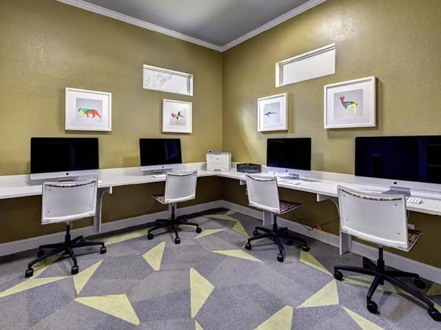 Four computers and chairs in a study area at The Village At Science Drive in Orlando Student Accommodation