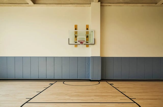 Basketball hoop on wall padded grey wall wooden court playing area at Seven07 in Champaign Student Accommodation