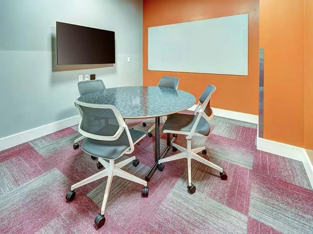 Round table four chairs whiteboard television meeting room at The Castilian in Austin Student Accommodation