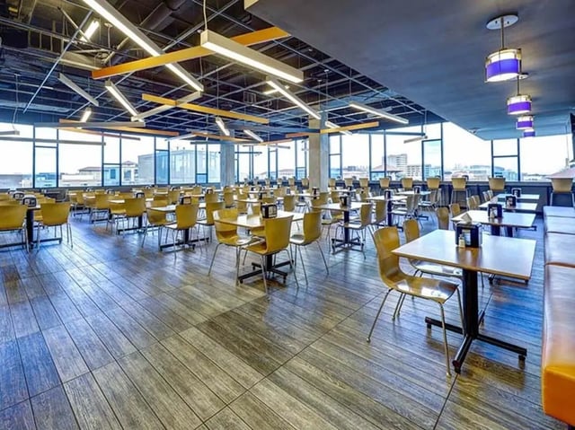 Tables chairs and orange booths communal area at The Castilian in Austin Student Accommodation