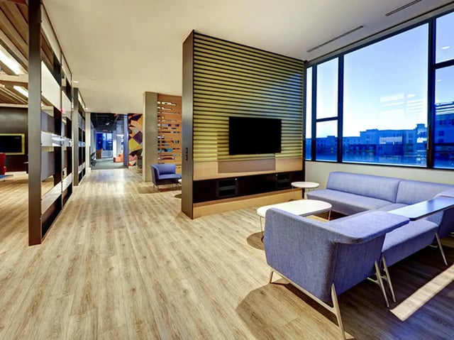 Blue sofas white tables wall mounted television living room at The Castilian in Austin Student Accommodation