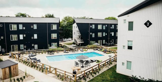 Apartment buildings with pool lounge chairs and umbrellas exterior at Muse Bowling Green in Bowling Green Student Accommodation