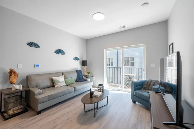 Gray sofa coffee table and blue chair living room at Muse Omaha in Omaha Student Accommodation