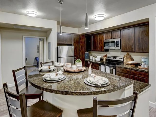 Kitchen island with chairs stainless steel appliances kitchen at The Village at Overton Park in Lubbock Student Accommodation