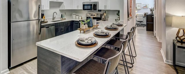 Modern kitchen with stainless steel appliances and bar stools kitchen at University Village at Boulder Creek in Boulder Student Accommodation