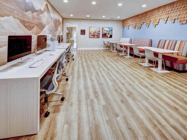 Computers and chairs at desk, colorful booths and tables lounge at University Village at Boulder Creek in Boulder Student Accommodation