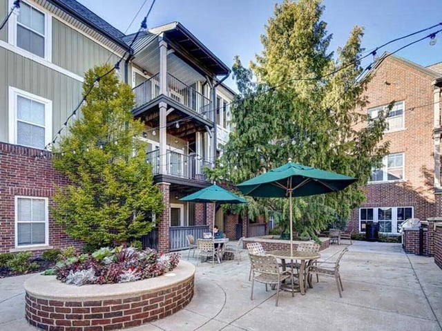 Patio furniture under umbrellas in courtyard exterior at The Lodges of East Lansing in East Lansing Student Accommodation