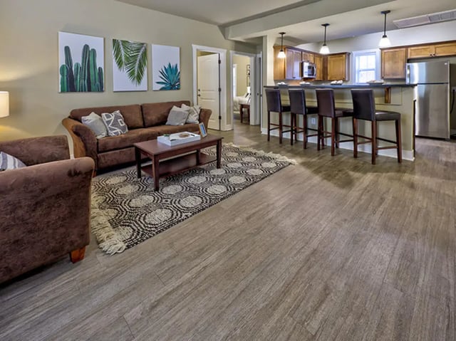 Sofa coffee table bar stools and kitchen living room at The Lodges of East Lansing in East Lansing Student Accommodation