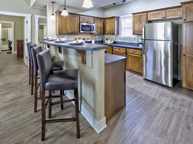 Bar stools kitchen island cabinets and refrigerator kitchen at The Lodges of East Lansing in East Lansing Student Accommodation